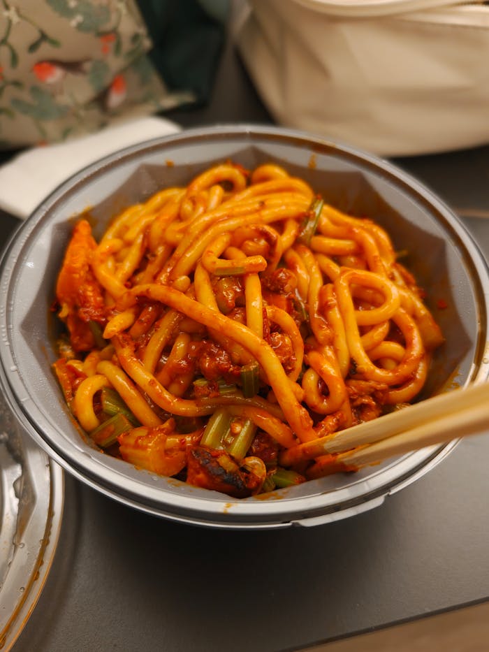 Delicious spicy noodles served in a bowl with chopsticks, perfect for a flavorful Asian meal.